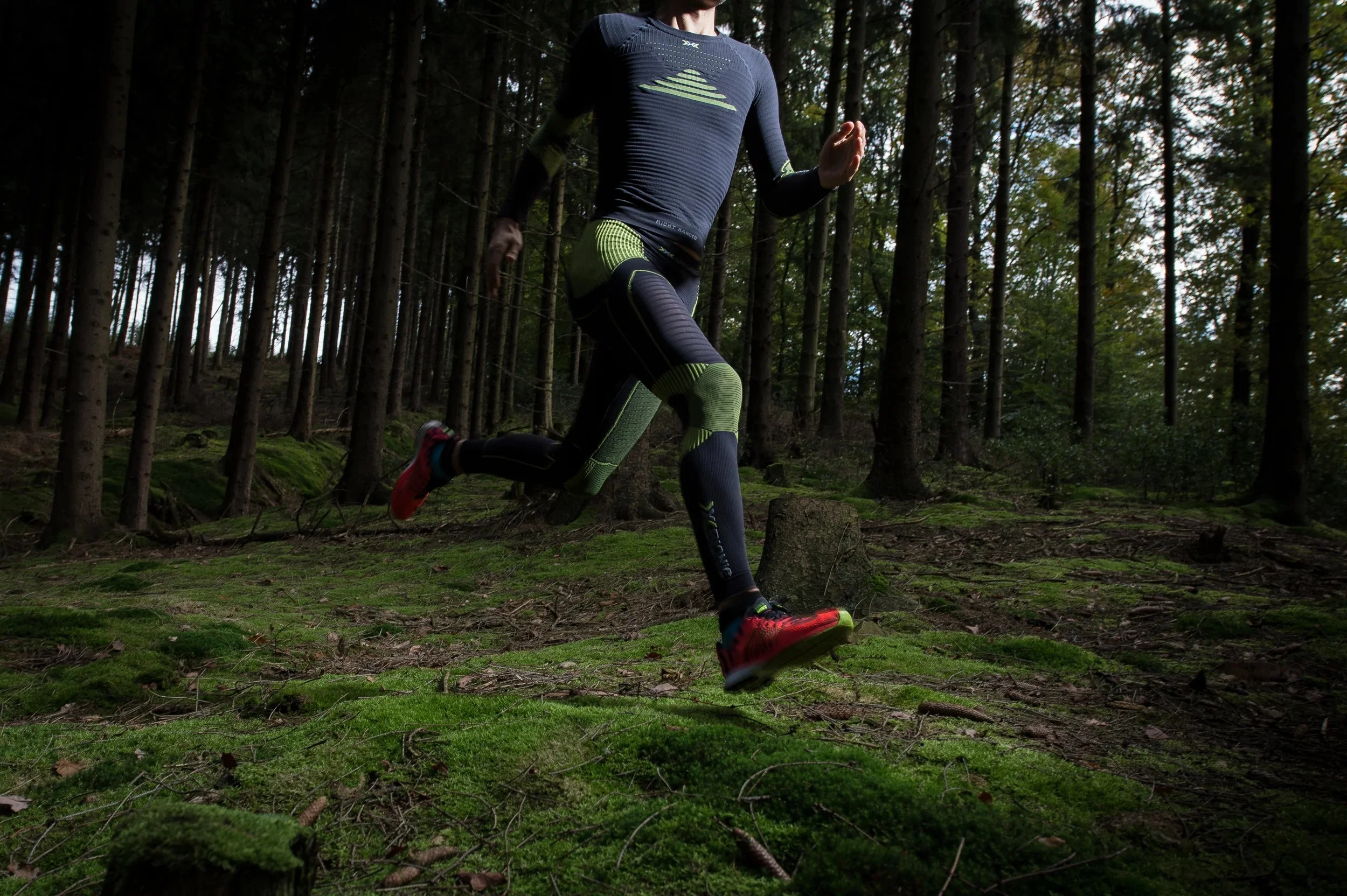 Low-angle shot of a runner in technical compression gear sprinting through a forest.